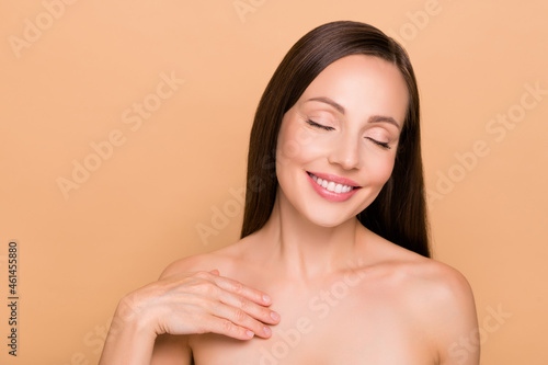 Portrait of attractive dreamy healthy cheery woman touching pure fresh skin isolated over beige pastel color background