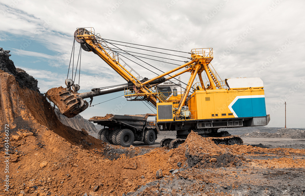 Large quarry dump truck. Big yellow mining truck at work site. Loading coal into body truck. Production useful minerals. Mining truck mining machinery to transport coal from open-pit production Large quarry dump truck. Big yellow mining truck at work site. Loading coal into body truck. Production useful minerals. Mining truck mining machinery to transport coal from open-pit production