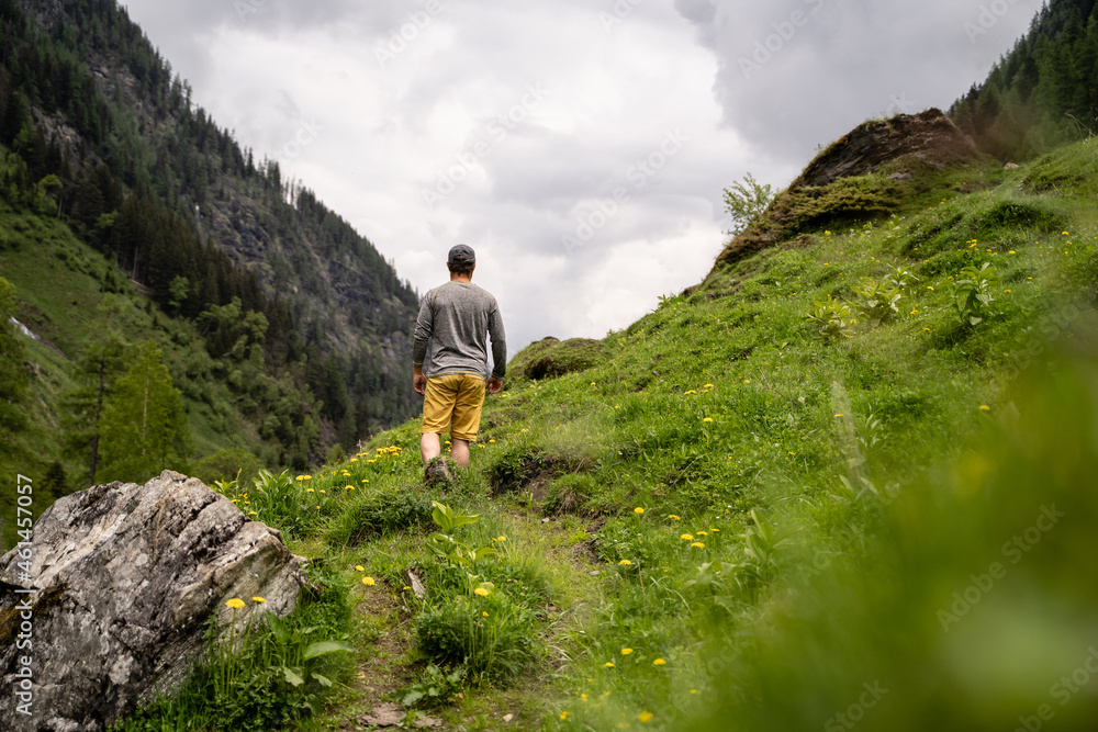 Junger Mann wandert auf Wanderweg in den Bergen von Salzburg bei bewölktem Wetter