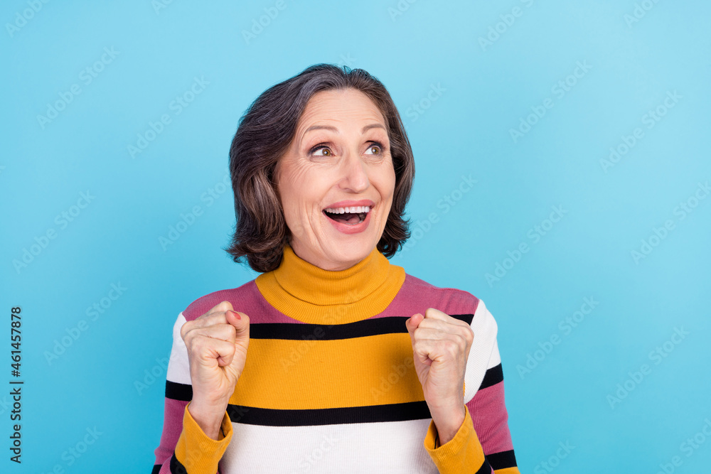 Photo of celebrate white hairdo elder lady hands fists look empty space wear striped pullover isolated on blue color background Photo of celebrate white hairdo elder lady hands fists look empty space wear striped pullover isolated on blue color background