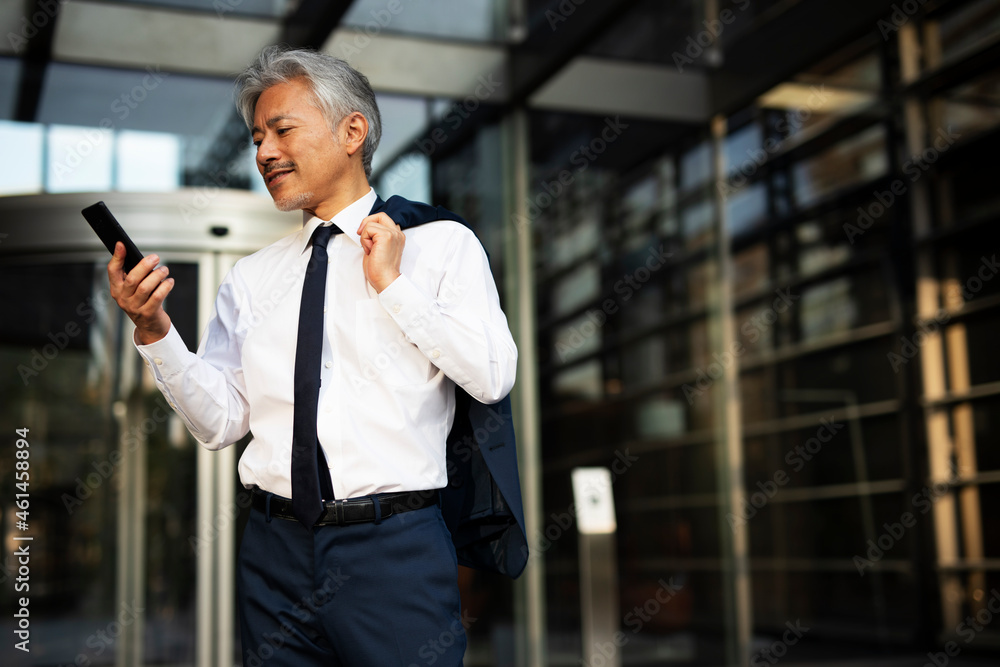 Naklejka premium Senior businessman outdoors. Middle-aged businessman using the phone..