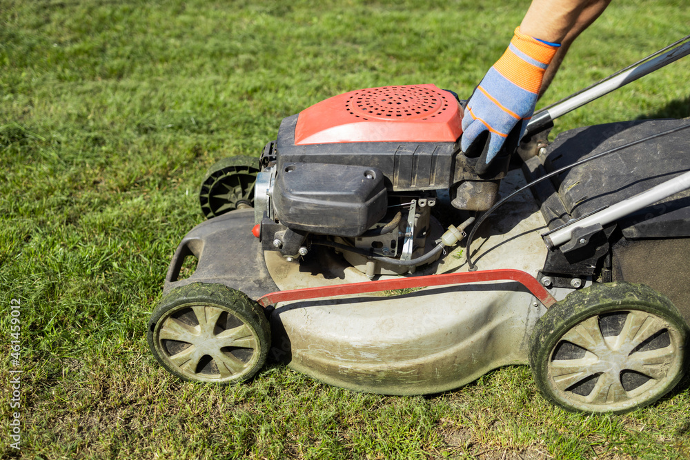 Gardener unscrews the plastic cap of the fuel tank in a lawn mower Gardener unscrews the plastic cap of the fuel tank in a lawn mower