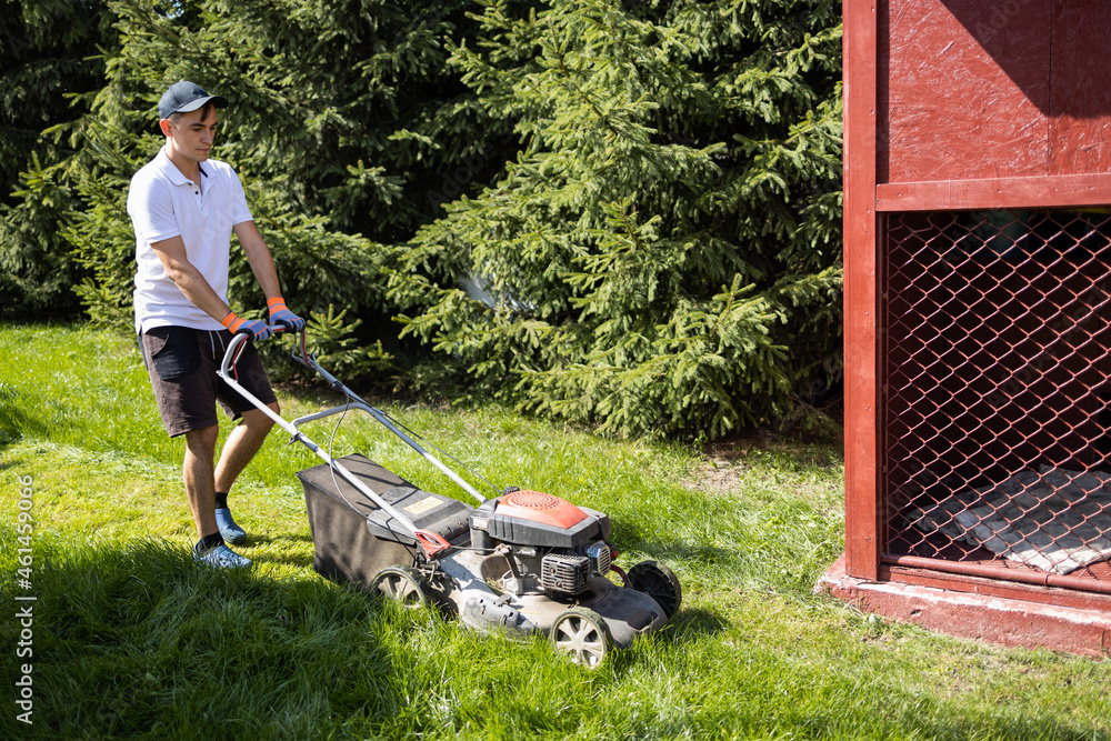 Young man using a gasoline lawn mower