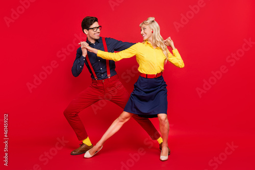 Full length body size view of attractive cheerful couple dancing twist festive day isolated over bright red color background photo