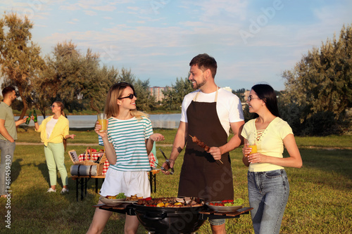 Group of friends cooking food on barbecue grill in park