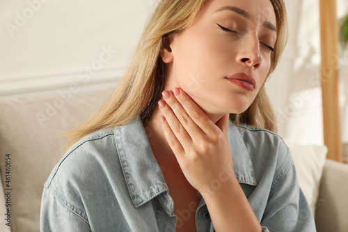 Young woman doing thyroid self examination at home