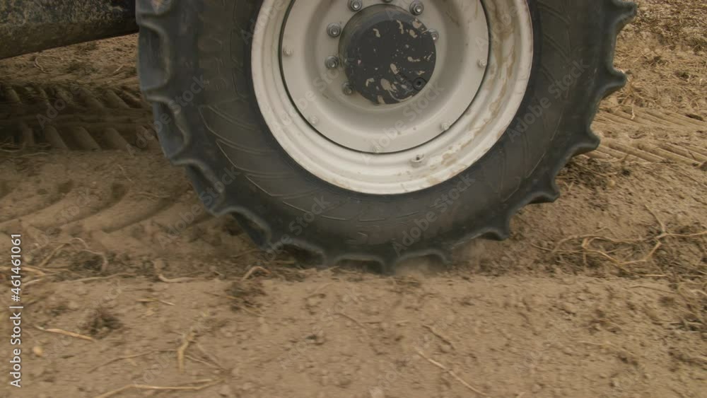 Close-up of a tractor wheel driving through the earth ground. Potatoes harvesting. Soil preparation. 4K slow motion. High quality 4k footage Close-up of a tractor wheel driving through the earth ground. Potatoes harvesting. Soil preparation. 4K slow motion. High quality 4k footage