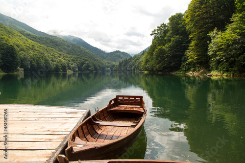 Old wooden boats are on the pier, on a beautiful mountain lake. © Plutmaverick