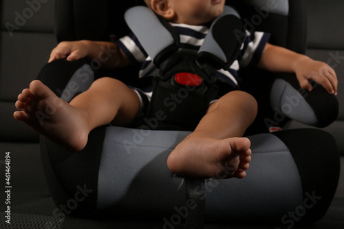Cute little boy sitting in child safety seat inside car, closeup