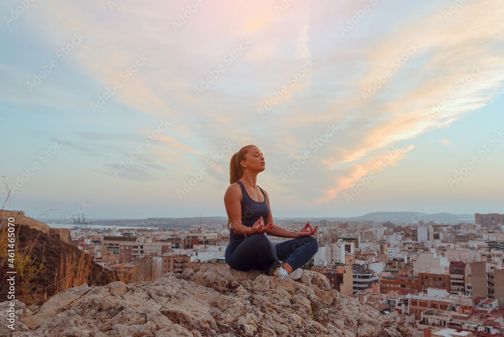 beautiful young woman does yoga outdoors, in nature in the city