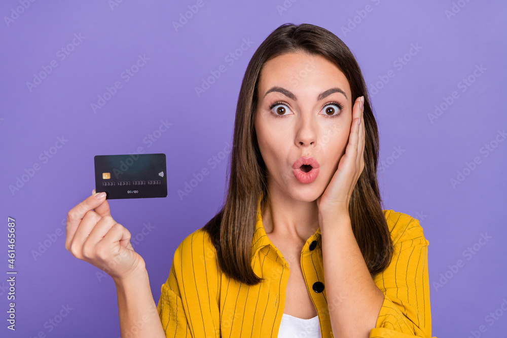 Photo of impressed young brunette lady hold card wear yellow shirt isolated on purple background Photo of impressed young brunette lady hold card wear yellow shirt isolated on purple background