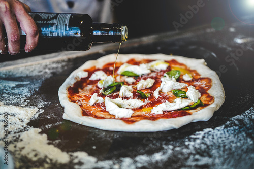 pizza chef preparing raw dough pizza olive oil basil mozarella fresh italian style napoletana napoli pizza about to be in oven