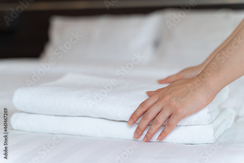 Closeup hands putting a stack of new clean bath towels on the bed. Hotel room service concept.
