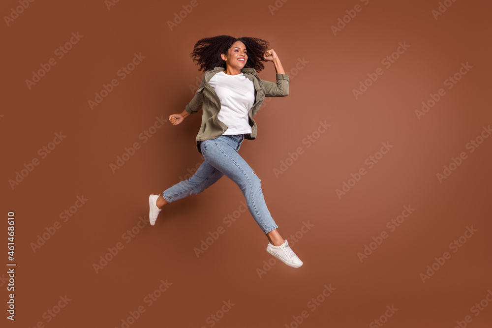 Full size profile photo of funky millennial brunette lady run wear shirt jeans shoes isolated on brown background