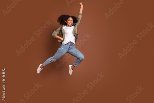 Full length portrait of carefree satisfied person raise fist toothy smile isolated on brown color background