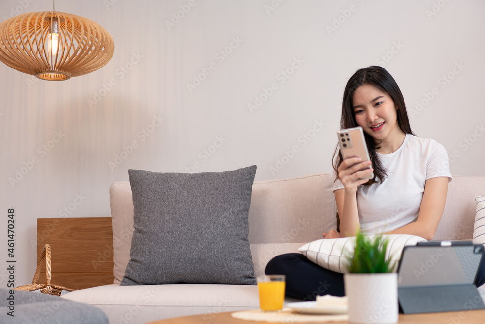 Living room concept a pretty girl sitting on the comfortable sofa spending her leisure on online with juice and snacks in the living room Living room concept a pretty girl sitting on the comfortable sofa spending her leisure on online with juice and snacks in the living room