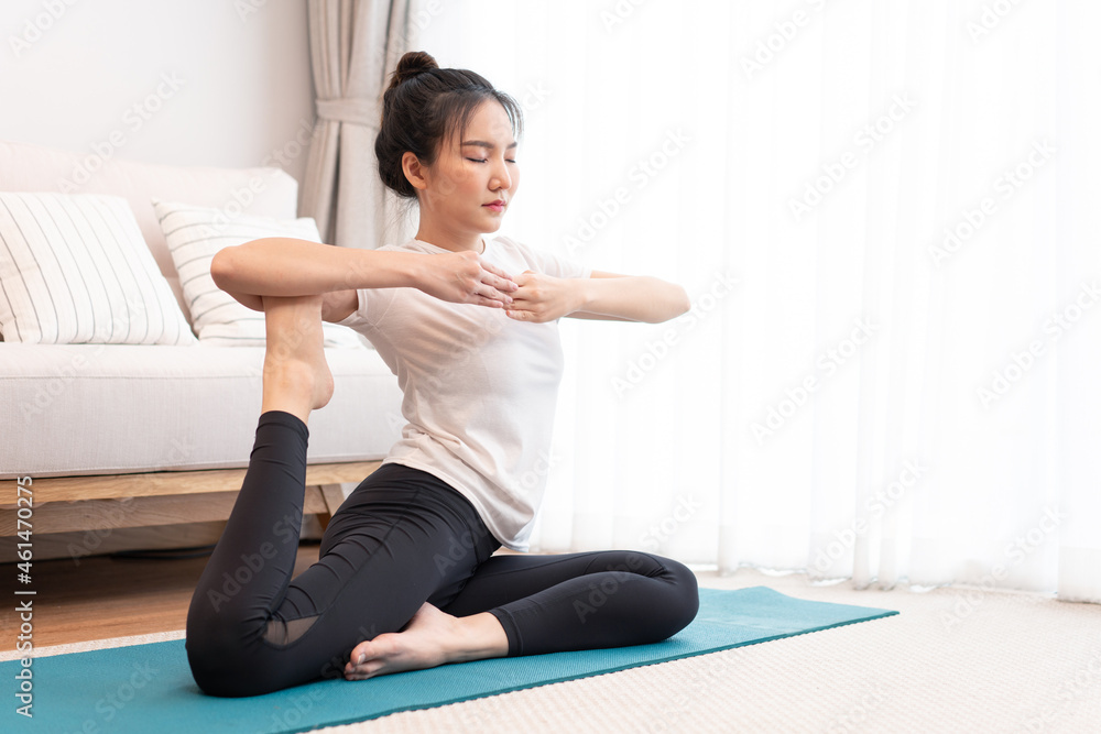 Fototapeta premium Productive activity concept a girl with a bun wearing the white t-shirt doing the difficult pilates move