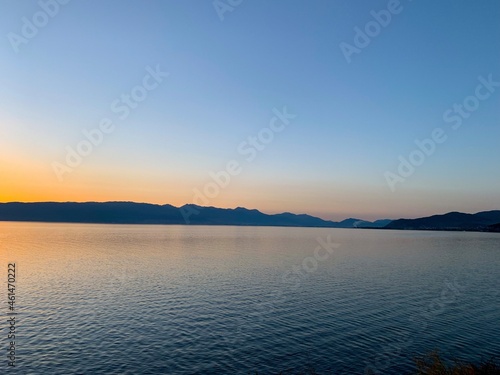 Idyllic orange sunset at the lake, silhouette of the mountains background © Oksana