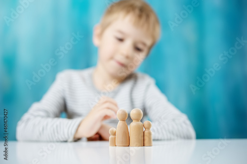 Child with wooden figures of the family on the blue background photo