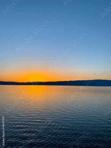 Idyllic orange sunset at the lake, silhouette of the mountains background © Oksana