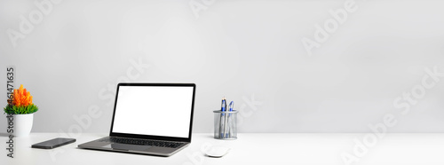 Working concept using technology, notebook, smartphones, devices. Blank white screen laptop on a white table in the office. Copy space on right for design or text, Closeup, Gray, and blur background