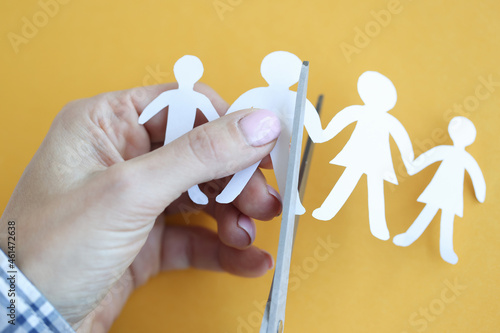 Woman hand cuts paper figures in form of family with scissors closeup photo