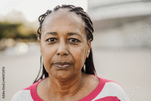 Senior african woman looking at camera outdoor in the city - Focus on face photo