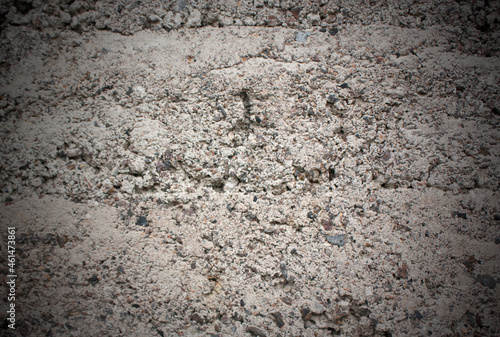 The old cinder-concrete wall is gray with damage and stones. Grey background with texture and vignette.