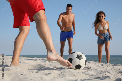 Group of friends playing football on beach