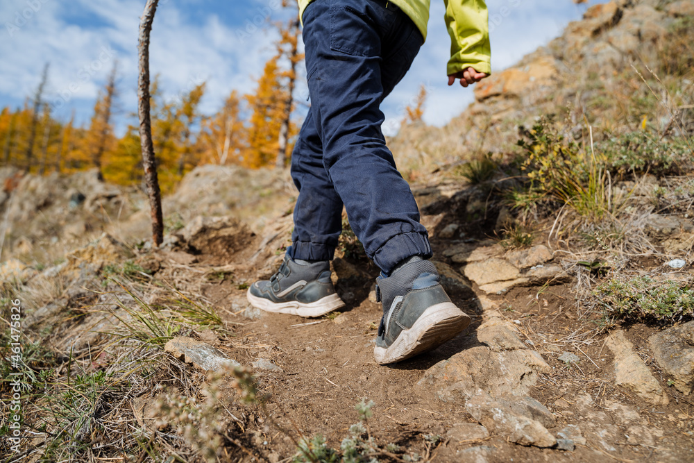 A close shot of the feet of a person climbing a mountain on a sunny autumn day, a walk in the mountains, active recreation, bright sportswear. A close shot of the feet of a person climbing a mountain on a sunny autumn day, a walk in the mountains, active recreation, bright sportswear.