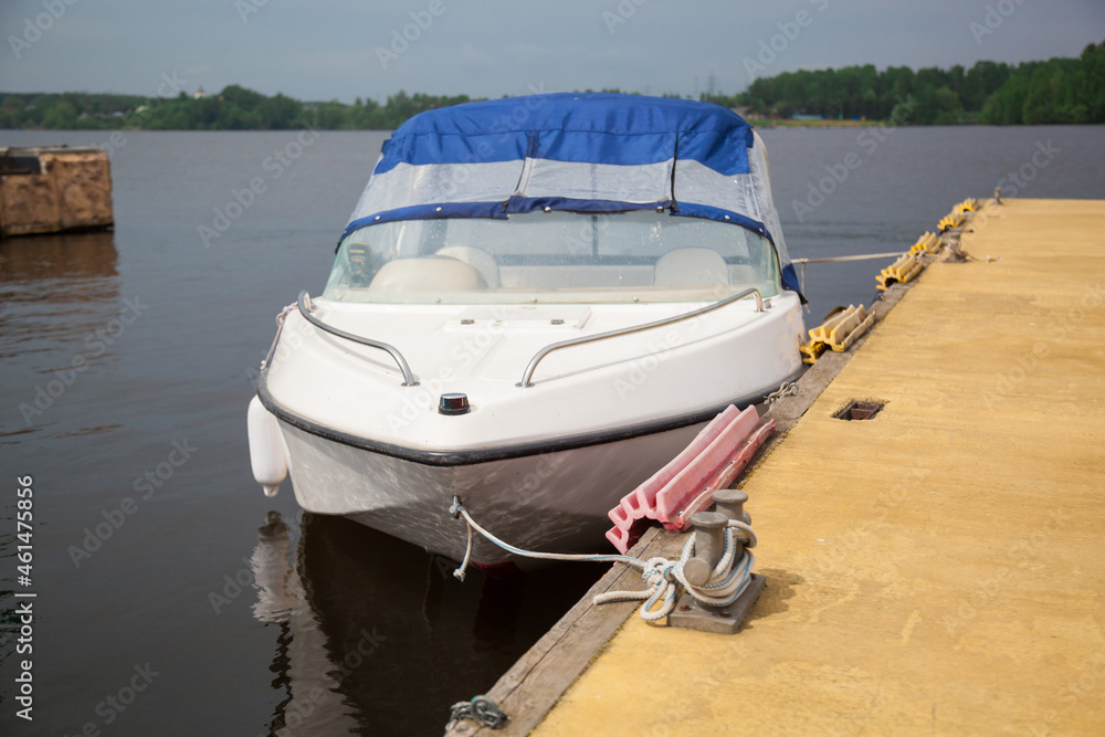 A white boat with a blue awning moored at the pier.