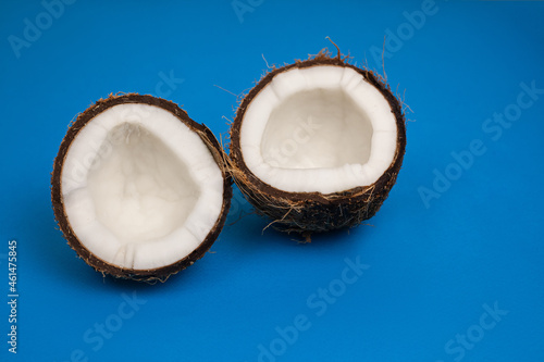halves of fresh coconut on a blue background.