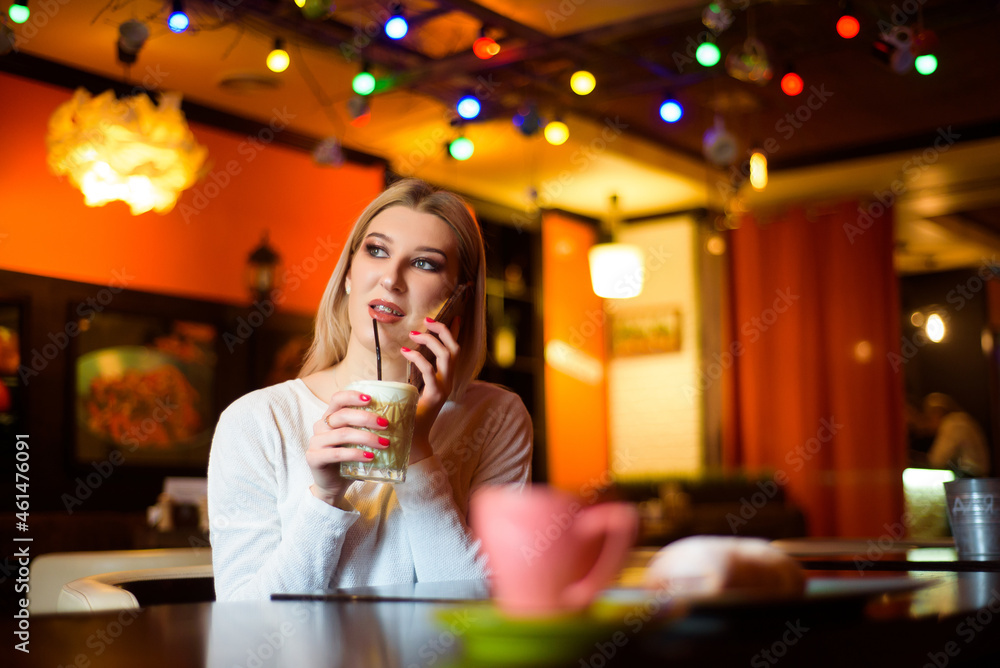 Woman drinking coffee and talks on the phone in a cafe. Woman drinking coffee and talks on the phone in a cafe.