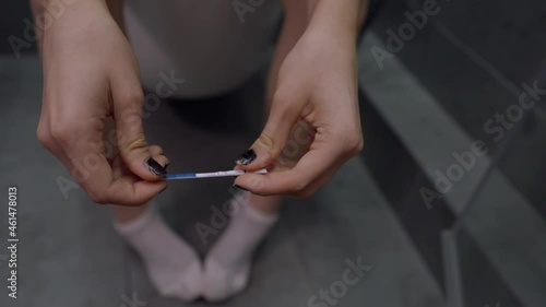 Woman sitting on the toilet twiddling with a piece of string