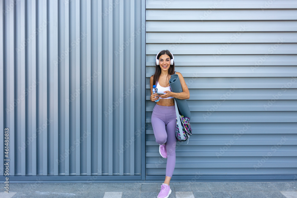 Image of a beautiful strong happy cheerful young sports woman posing texting with bottle of water .Happy young woman in sports clothing smiling. Muscular fitness model Image of a beautiful strong happy cheerful young sports woman posing texting with bottle of water .Happy young woman in sports clothing smiling. Muscular fitness model