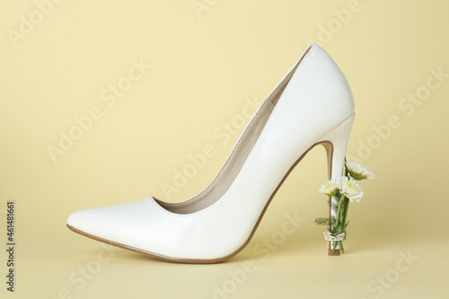 Stylish women's high heeled shoe with beautiful flowers on pale yellow background