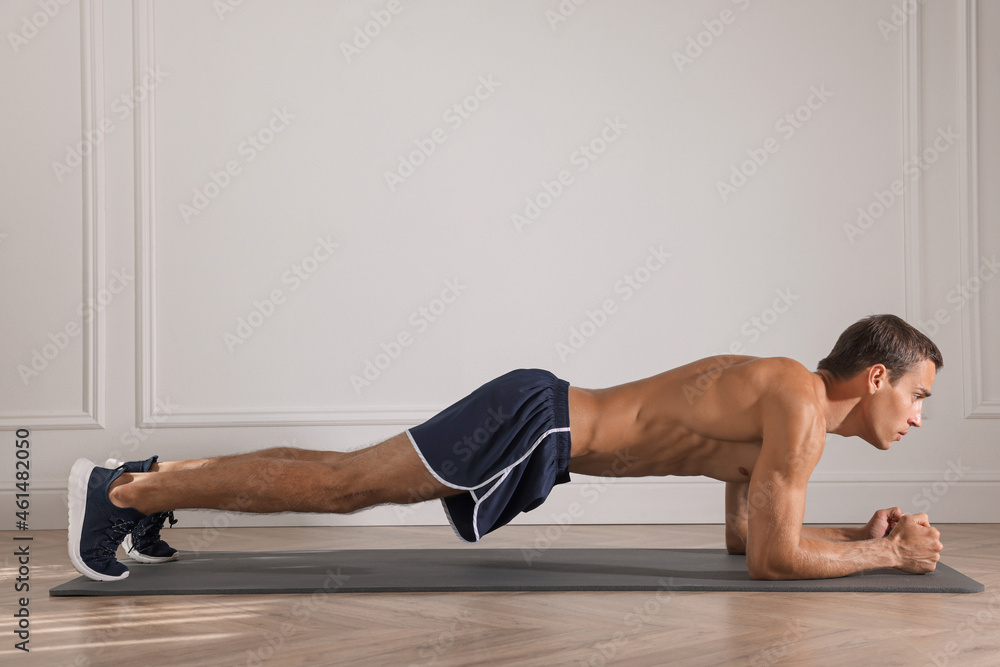 Handsome man doing plank exercise on floor indoors Handsome man doing plank exercise on floor indoors