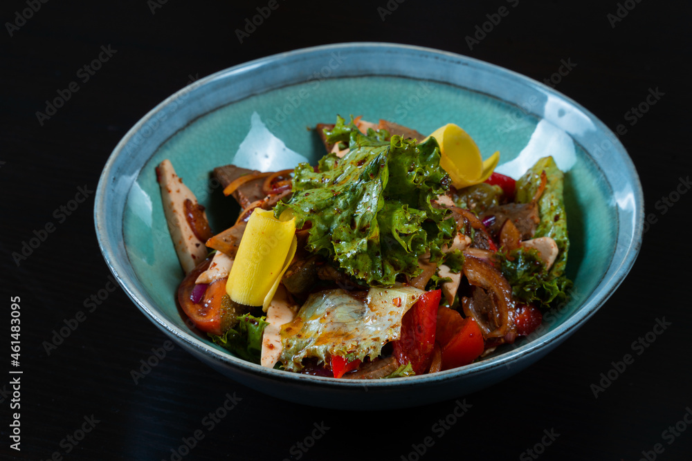Salad with meat and vegetables on a black background Salad with meat and vegetables on a black background