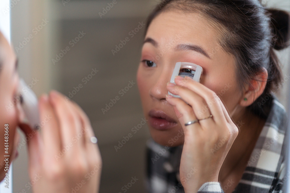 Charming ethnic woman using eyelash curler Charming ethnic woman using eyelash curler