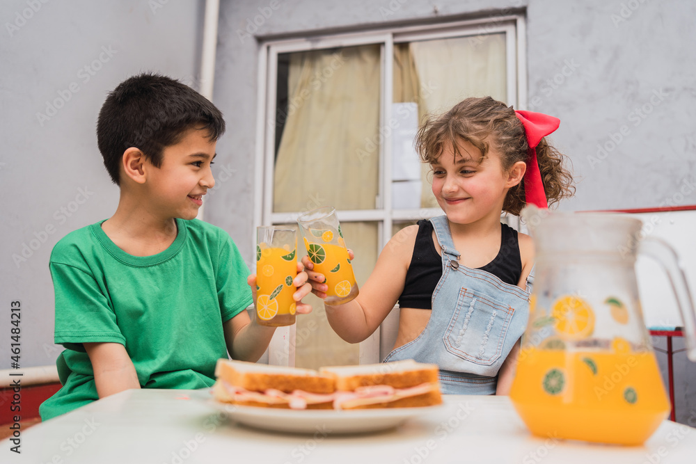 Happy kids clinking with juice near sandwiches Happy kids clinking with juice near sandwiches