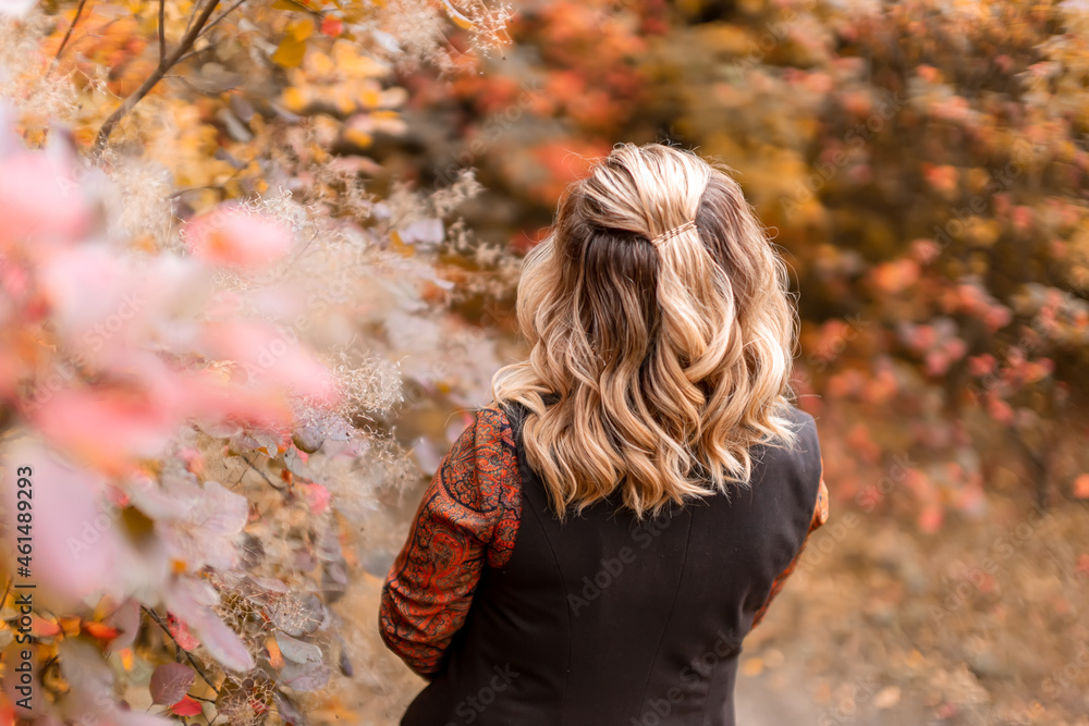 a young woman stands with her back against the background of an autumn park a young woman stands with her back against the background of an autumn park