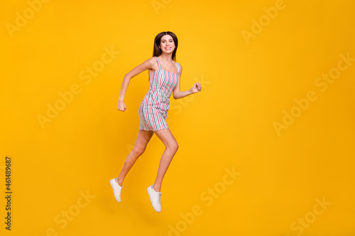 Full length body size woman smiling jumping high happy running fast cheerful isolated vivid yellow color background