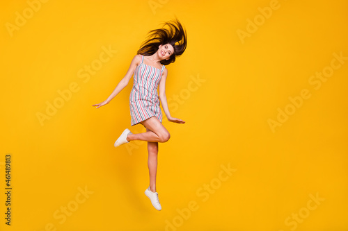 Full length body size woman smiling jumping high happy throwing hair isolated vivid yellow color background