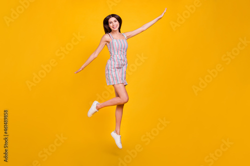 Full length body size woman smiling jumping high happy playful overjoyed isolated vivid yellow color background