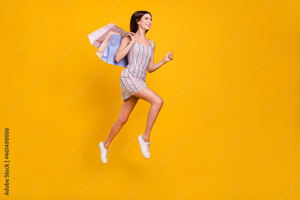 Full length body size woman smiling jumping running on sale with bags isolated vivid yellow color background