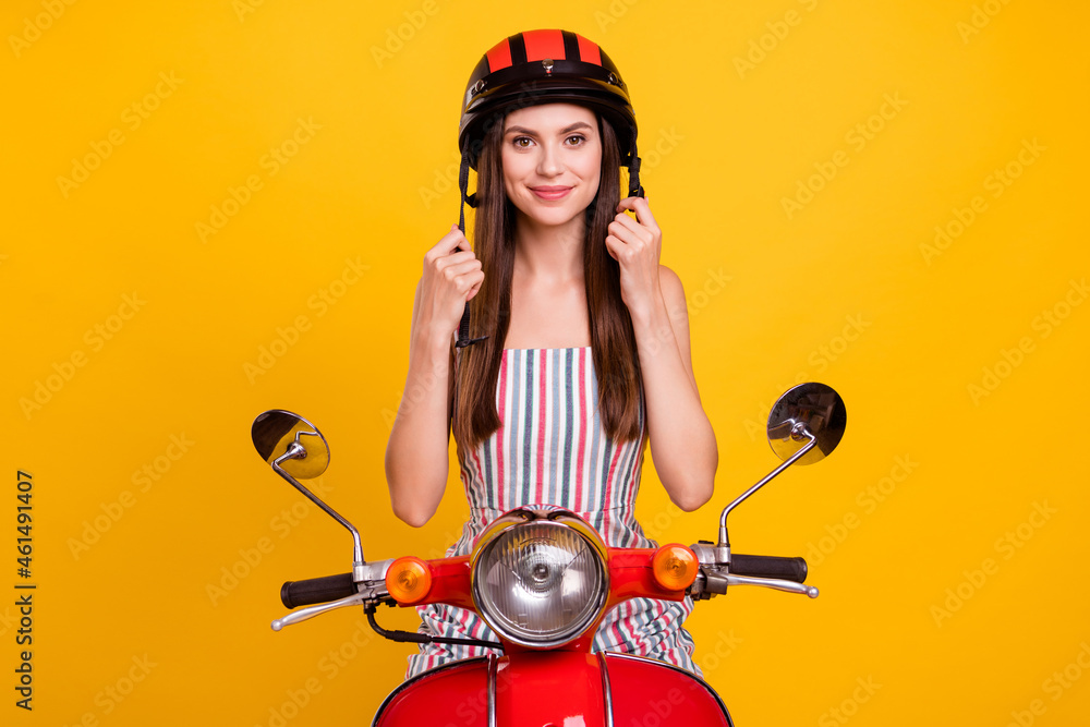 Photo portrait young woman driving bike in striped dress taking on helmet isolated bright yellow color background