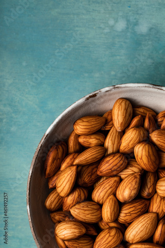 A closeup overhead view of a bowl of almonds shot on a blue background photo