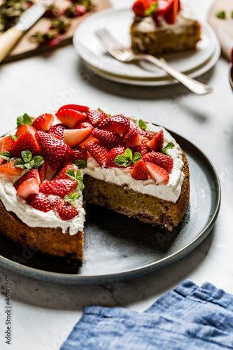 A homemade strawberry cake on a black plate and marble worktop. Made with almond flour.