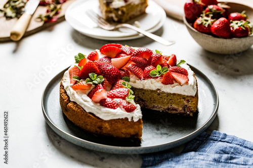 A homemade strawberry cake on a black plate and marble worktop. Made with almond flour. photo