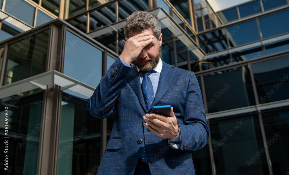 nervous entrepreneur in businesslike suit looking at phone outside the office, anxiety nervous entrepreneur in businesslike suit looking at phone outside the office, anxiety